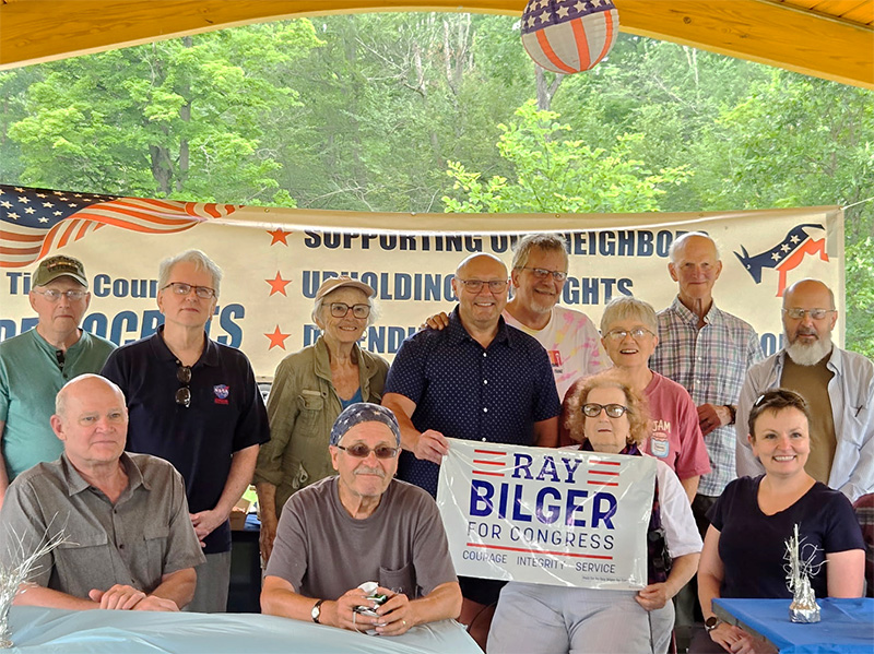 Group photo at an outdoor picnic pavillion with Ray and friends holding a campaign sign.